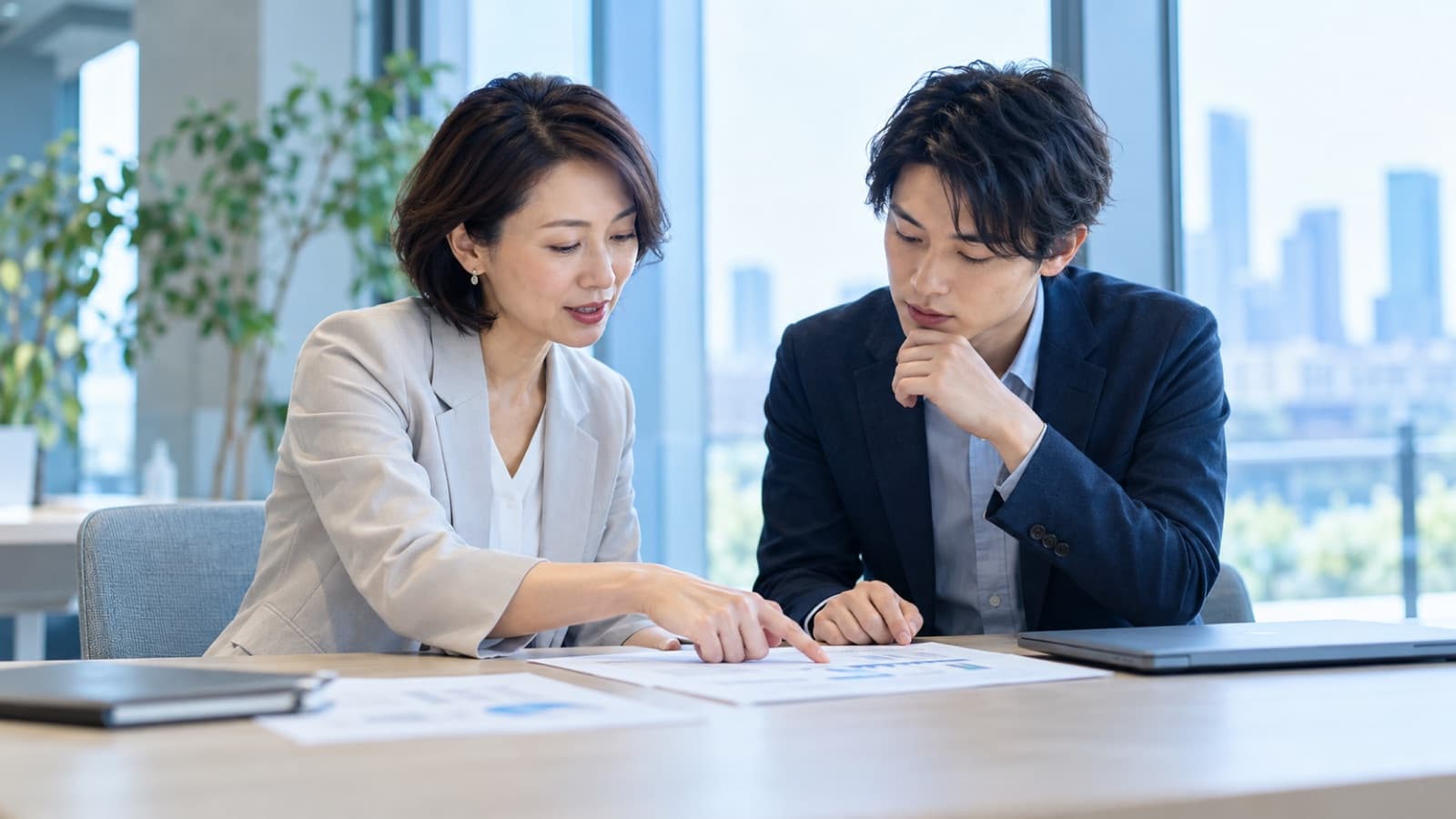 上司と若手社員が書類を一緒に確認している様子