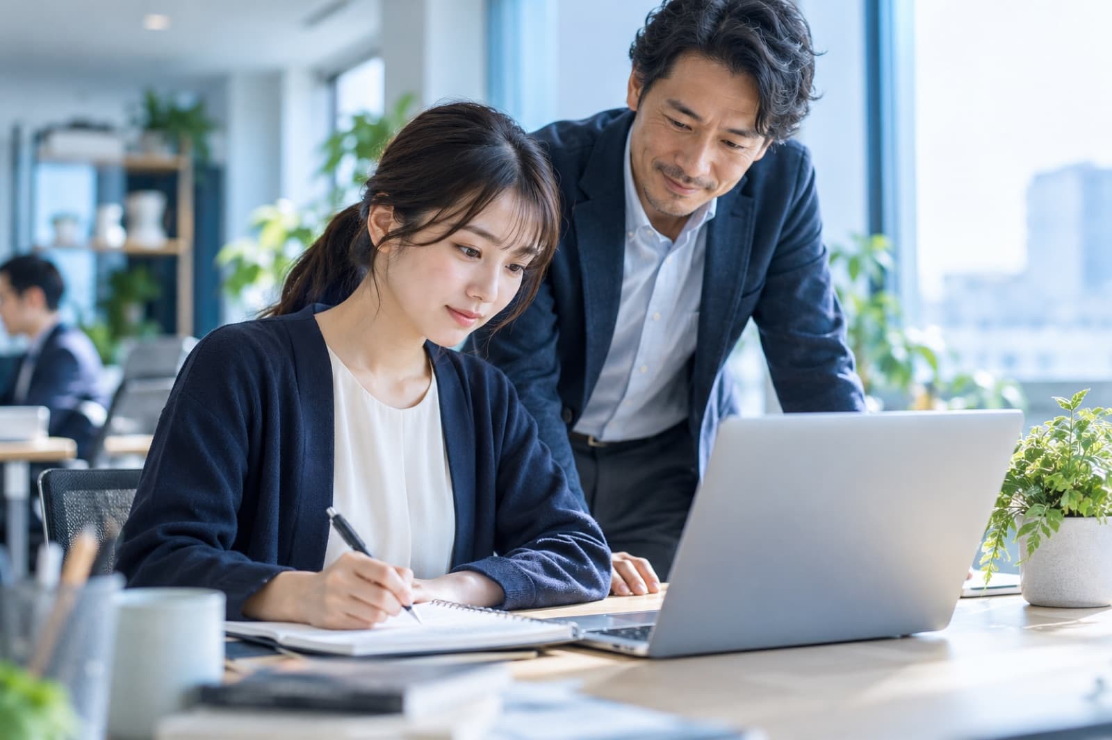 新人社員が学び、先輩が見守っている様子